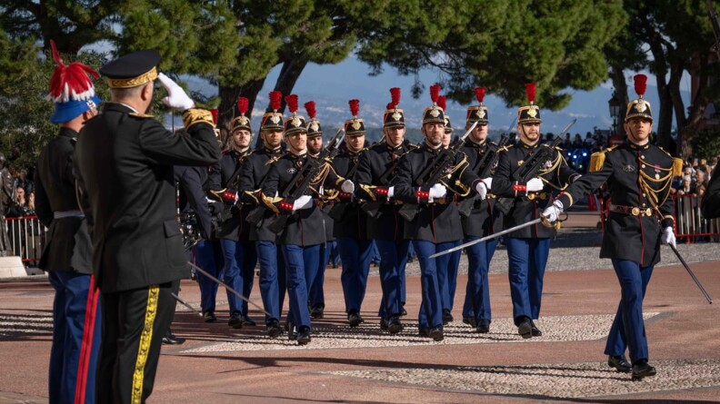 Un détachement de fantassins de la garde républicaine passent au pas devant deux autorités. L'officier devant ses troupes salue au sabre