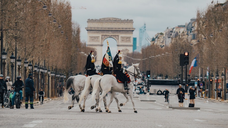 Trois chevaux blancs de la Garde Républicaine portant le drapeau sur les CHamps Elysées
