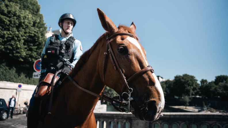 Photo d'un cavalier de la garde r&eacute;publicaine sur sa monture, un cheval brun, dont on la t&ecirc;te apparait en premier plan, dans les rues de Paris
