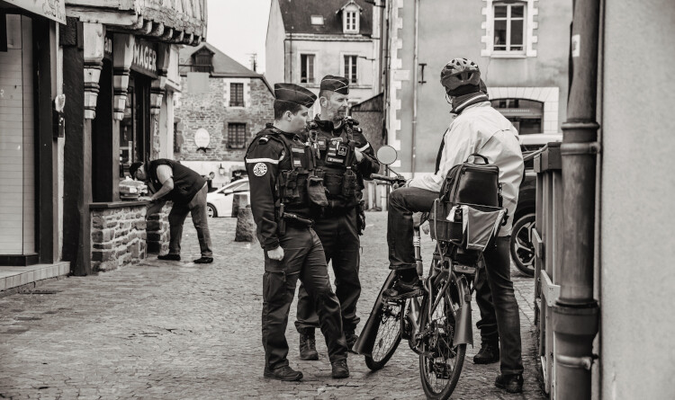 Agrandir l'image Deux gendarmes discutant avec un monsieur à vélo dans la rue.