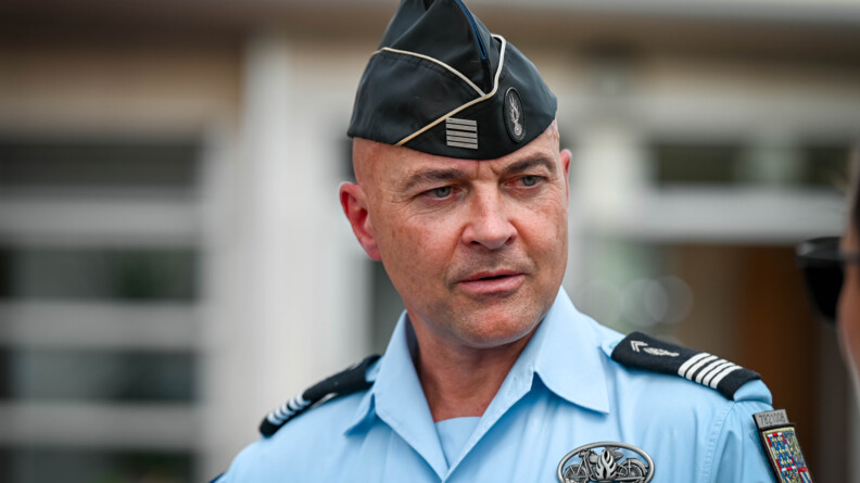 Un officier de gendarmerie se tient face à l'objectif. Il porte un calot noir sur la tête et une chemise bleu ciel ornée de diverses insignes.