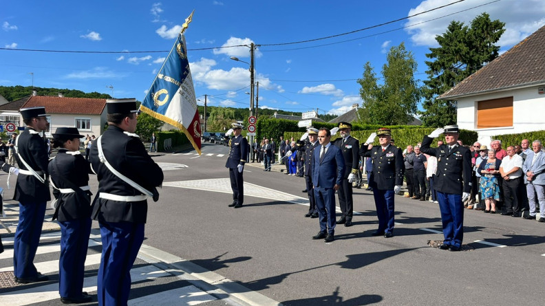 Le ministre des Arm&eacute;es, entour&eacute; des autorit&eacute;s militaires au garde-&agrave;-vous, rend les honneurs au drapeau, port&eacute; par la garde au drapeau, compos&eacute;e de trois gendarmes vus de trois-quarts dos.