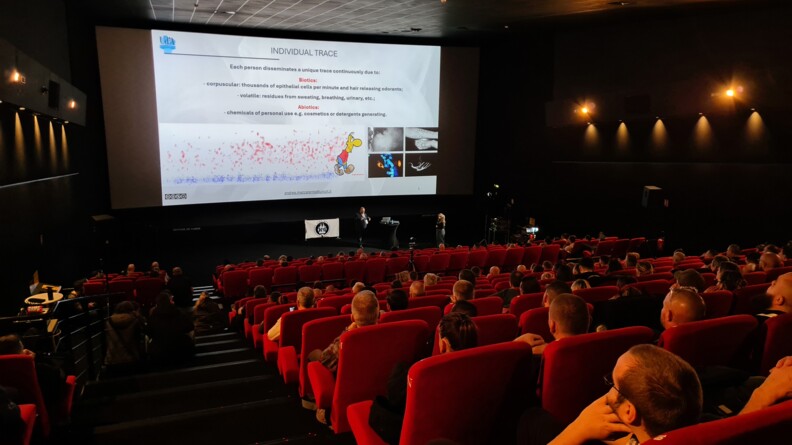 un amphith&eacute;&acirc;tre aux fauteuils rouges avec du public devnat un &eacute;cran pr&eacute;sentant des donn&eacute;es