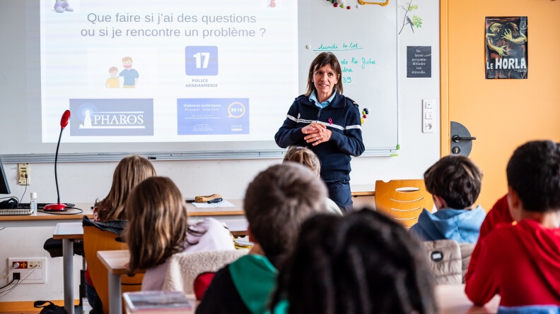Une gendarme de face dans une salle de classe face à plusieurs élèves