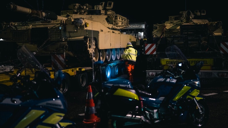 Un homme inspecte un des chars. En premier plan se trouve des motos de la gendarmerie.