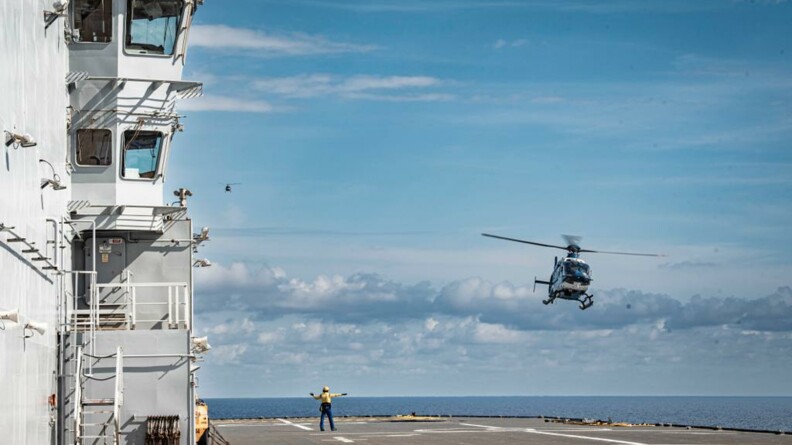 Un hélicoptère de la gendarmerie nationale en approche du pont du porte hélicoptère Mistral de la Marine nationale, d'où un signaleur le guide.