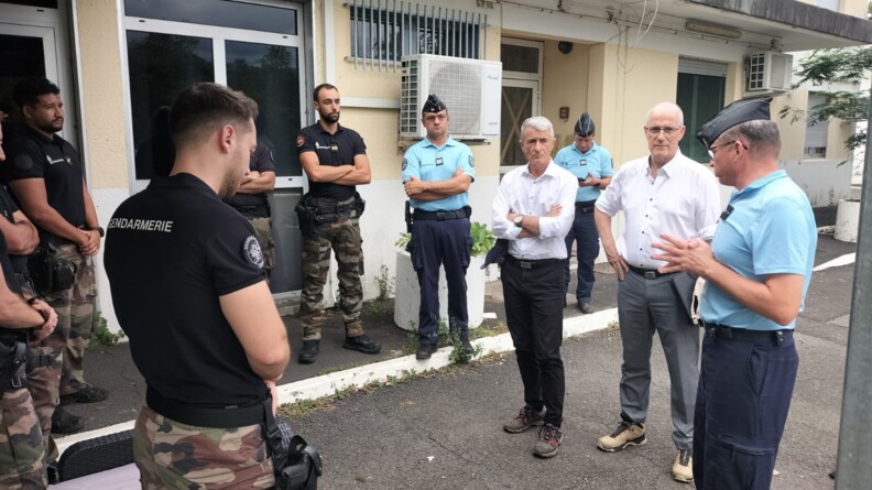 Des gendarmes discutent avec des personnes civiles, debout dans la rue, apr&egrave;s le passage du cyclone Garance sur l'&icirc;le de la R&eacute;union.