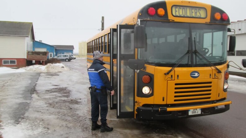 Agrandir l'image Un gendarme devant un bus jaune sur lequel est indiqué : écoliers.