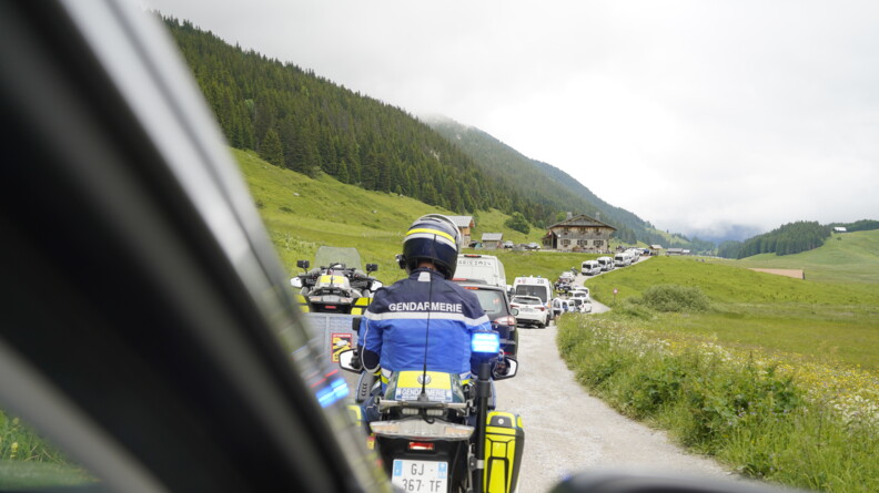 Un motard de la gendarmerie à la fin du cortège de la flamme olympique sur la route traversant un paysage savoyard