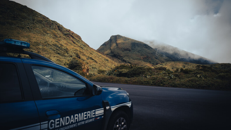 Agrandir l'image Un Duster sérigraphié gendarmerie, vu trois quart arrière droit, devant un paysage de colline et d'herbe, le tout recouvert par la brume