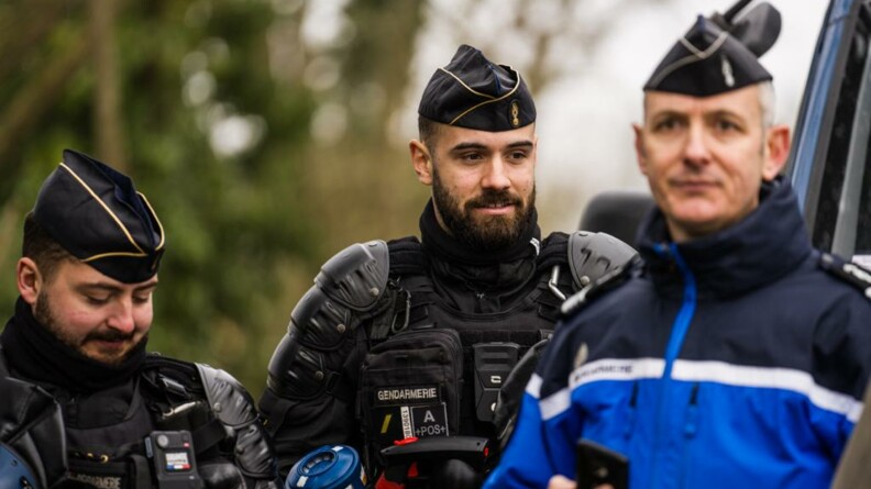 Trois gendarmes de face et en extérieur. Parmi eux, deux mobiles en tenue d'intervention et un gendarme départemental en tenue de service courant.