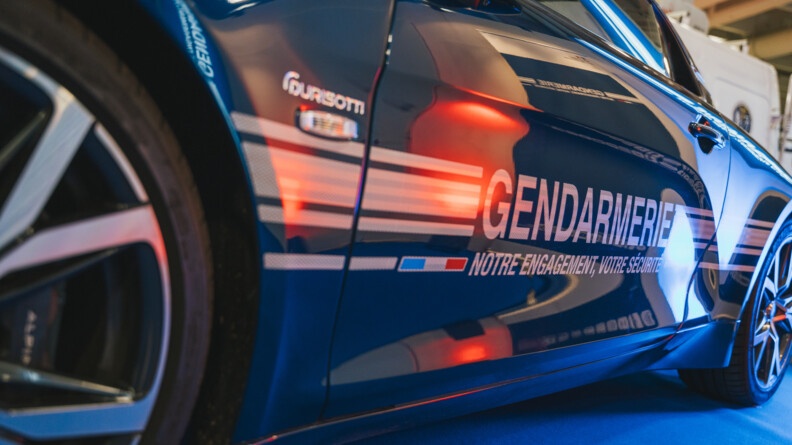 Photo en gros plan de la portière d'une Alpine de la gendarmerie de couleur bleue, portant une sérigraphie de la gendarmerie avec la mention "Notre engagement, votre sécurité". Photo prise lors du salon de l'Auto 2024, à Paris.