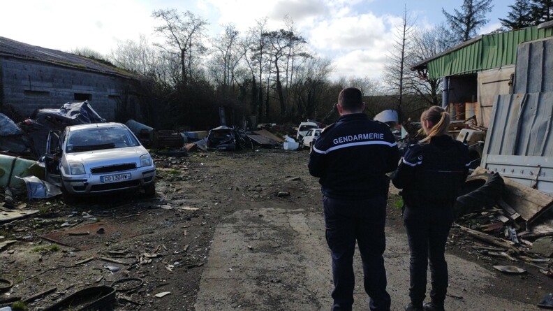 A droite de la sc&egrave;ne, deux gendarmes, un homme et une femme, de dos, devant une d&eacute;charge sauvage