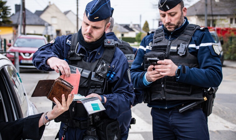 Un policier municipal et un gendarme contr&ocirc;lent un v&eacute;hicule dont la conductrice leur tend les papiers.