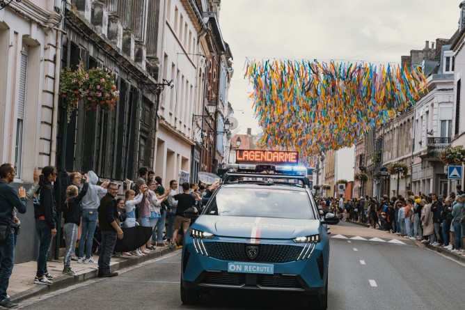 Agrandir l'image Véhicule de la caravane gendarmerie avançant dans une rue décorée.