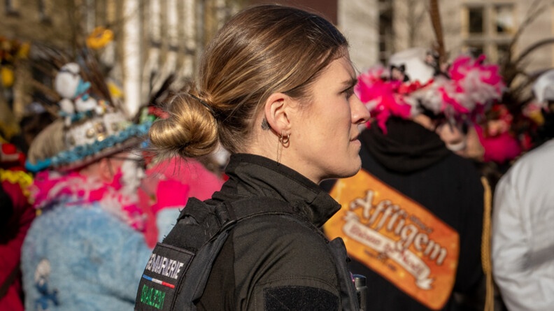 Photo d'une femme gendarme, debout, au milieu de carnavaleux, lors du carnaval de Bergues