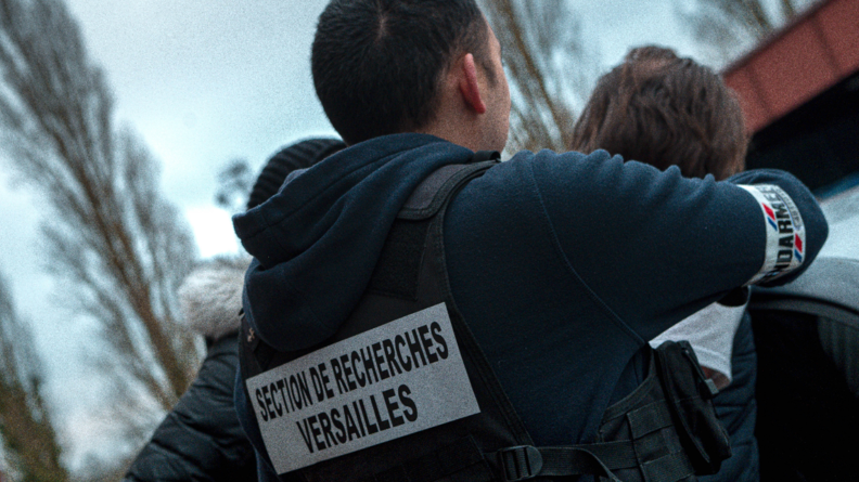 Un gendarme de dos avec noté sur son sweat : section de recherches Versailles.