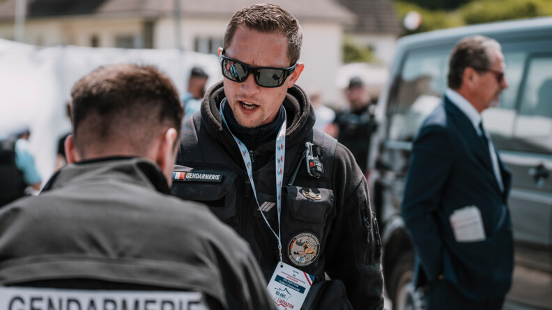 Deux gendarmes : en premier plan l'un est de dos et flou et l'autre est de face et net et porte un badge "Déminage". Ils sont en tenue sombre.