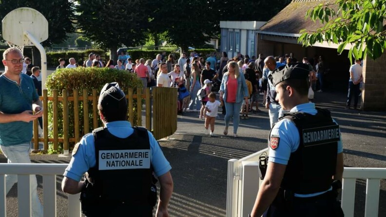 Agrandir l'image Deux gendarmes devant une école primaire abordent un responsable éducatif.