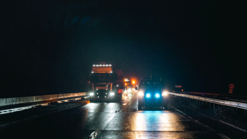 Le convoi en train d'avancer. En premier plan, une voiture de gendarmerie ouvre le cortège. Il fait nuit et il pleut.