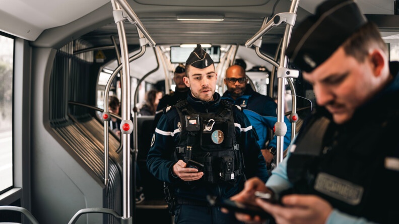 Agrandir l'image Deux gendarmes français, accompagnés d'un policier suisse, effectuent un contrôle des passagers dans un autobus.