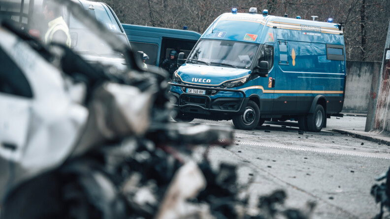 Vue derrière une barricade floue, sur un véhicule de maintien de l'ordre