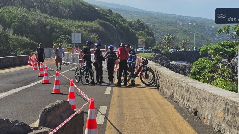 Des gendarmes &agrave; v&eacute;lo &eacute;changent avec des habitants sur un pont, sur lequel des plots sont align&eacute;s, et un ruban a &eacute;t&eacute; install&eacute;, apr&egrave;s le passage du cyclone Garance sur l'&icirc;le de la R&eacute;union.