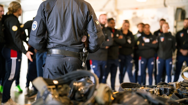 Un homme du GIGN de dos, face à lui, flous, les sportifs de haut niveau