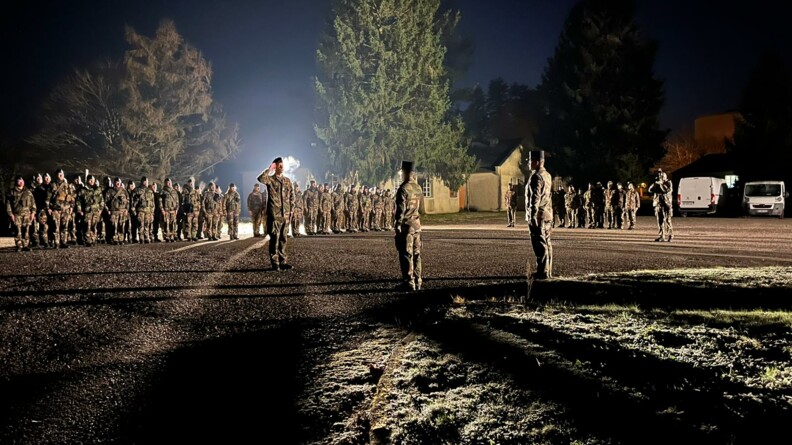 Une cinquantaine de gendarmes align&eacute;s lors d'une c&eacute;r&eacute;monie de nuit. L'un d'entre eux, un peu plus avanc&eacute;, fait le salue militaire.