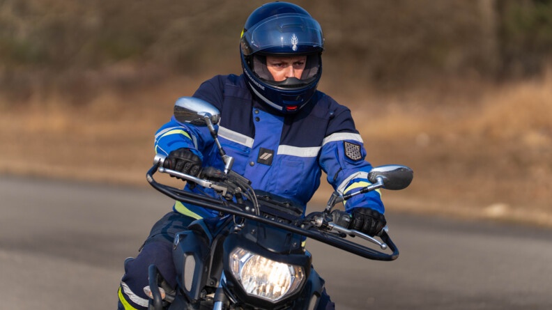 un motard de la gendarmerie tenant le guidon de sa moto et regardant au loin