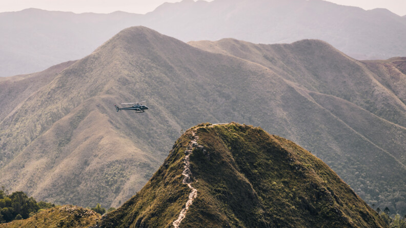 Hélicoptère de la SAG de Nouméa volant face à une montagne.