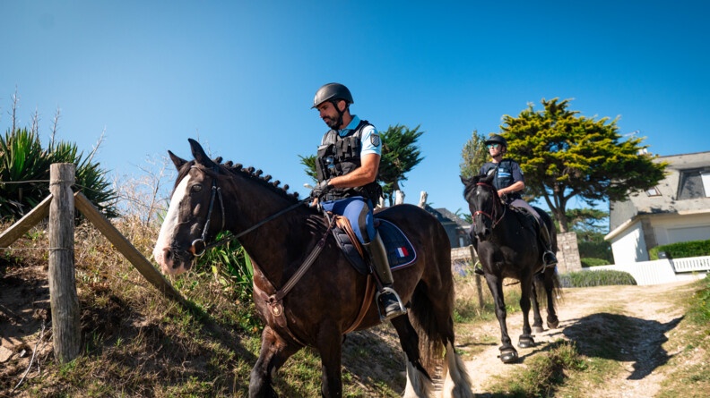 Un gendarme et une policière municipale surveillent une plage à cheval.