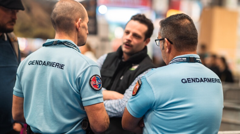 Deux référents sûreté discutent avec un exposant, au salon international de l'agriculture.