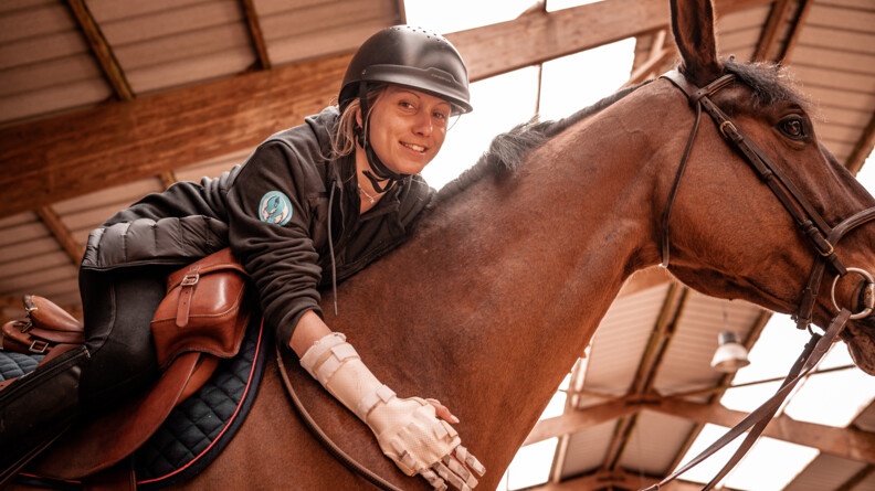 Claire, participante au stage Cent'Or, sur son cheval, sa main blessée par balle au premier plan.