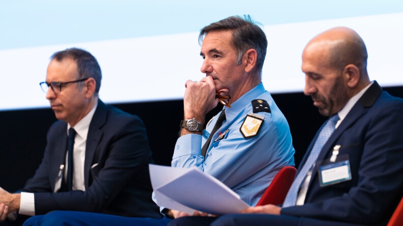 Photo de trois intervenants, dont un gendarme, situ&eacute; au centre, lors de la table ronde du colloque