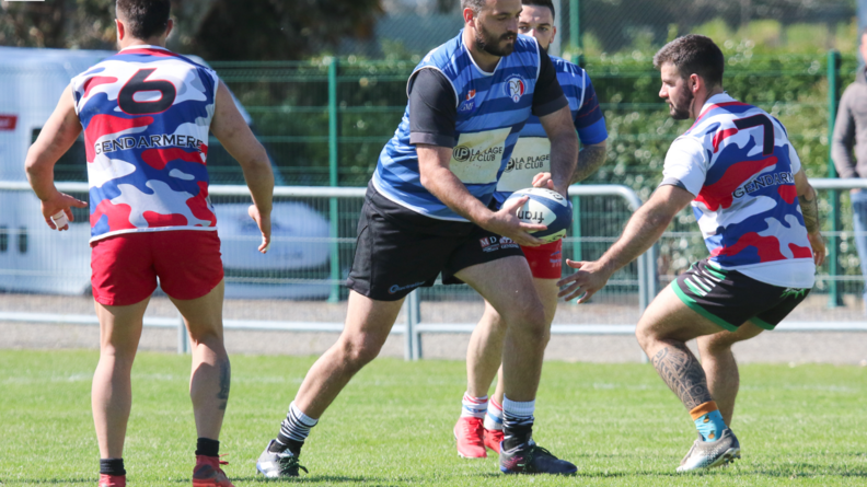 quatre hommes en tenue de sport s'entra&icirc;nent au rugby, les deux au centre contre les deux aux ext&eacute;rieurs. Celui du milieu tient le ballon &agrave; deux mains et s'appr&ecirc;te &agrave; faire une passe
