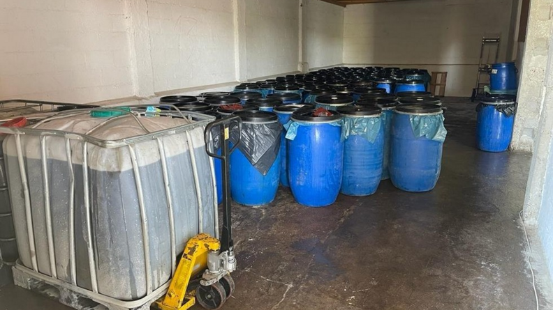 Plusieurs fûts d'huile de friture usagée entreposés dans un hangar.