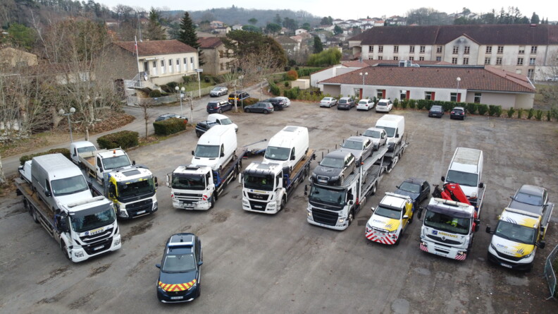 Vue en plong&eacute;e sur six camions et deux d&eacute;panneuses transportant des v&eacute;hicules saisis
