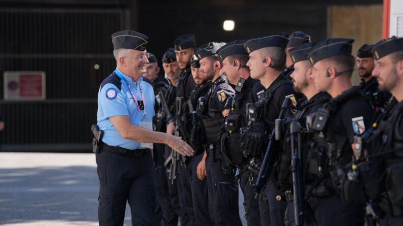 Un général 5 étoiles de la de gendarmerie s'apprête à serrer la main d'un gendarme qui  est aligné avec une quinzaine d'autres gendarmes mobiles en noir