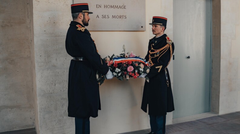 Agrandir l'image Deux gendarmes portent une couronne mortuaire devant la plaque en hommage aux morts de la gendarmerie