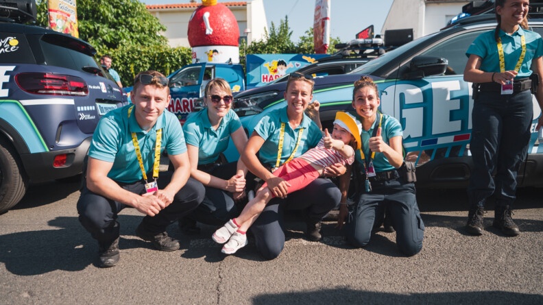 Agrandir l'image La petite Tiphaine avec les gendarmes de la Caravane du Tour de France au milieu des véhicules de la caravane.