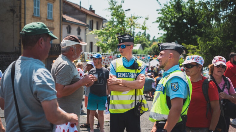 Deux gendarmes échangent avec les gens venus nombreux assister aux passages de la caravane et des courreurs.