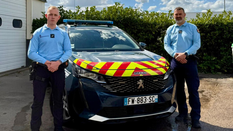 Agrandir l'image Deux gendarmes, les mains devant, de part et d'autre d'un véhicule d etype 4x4 sérigraphié gendarmerie. AU fond, une haie, à gauche, des portes blanches de garage