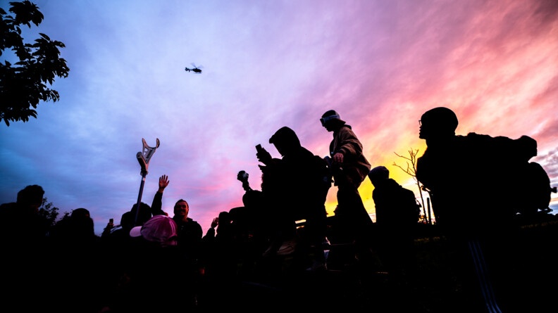 Des ravers regardent l'hélicoptère de la gendarmerie avec un magnifique coucher de soleil