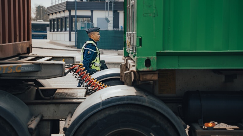 Un gendarme entre deux conteneurs de camion lors d'un controle routiers.