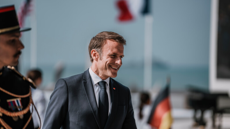 Image du président de la République en train de sourire avec à sa gauche, le profil d'un garde républicain en tenue d'apparat.