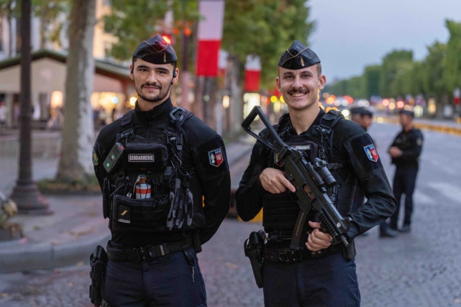 Agrandir l'image Deux gendarmes mobiles se tiennent debout côte à côte sur les Champs-Elysées, à Paris, alors que le jour commence à décliner
