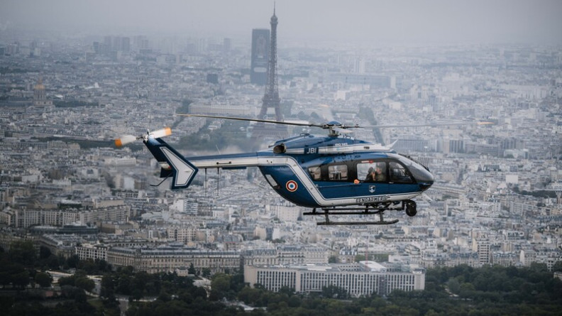 La photo représente un hélicoptère bleu de la gendarmerie survolant Paris