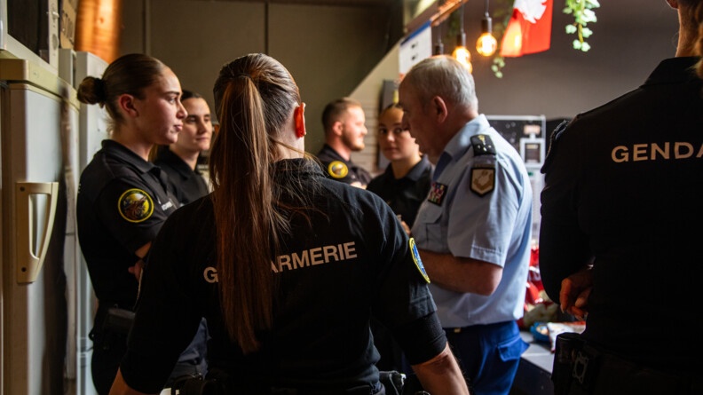 Agrandir l'image Le directeur général de la gendarmerie, de profil, entouré de plusieurs gendarmes mobiles féminins.