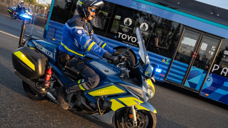 Agrandir l'image Motocycliste de la gendarmerie à côté du bus des para athlètes de la France.
